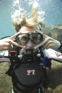 Scuba diver adjusting goggles underwater