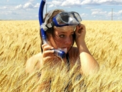 Girl with a scuba mask looking around a wheat field